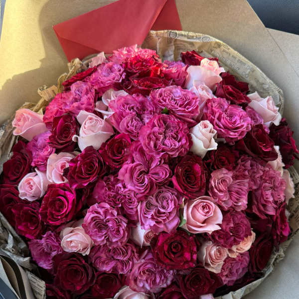 Bouquet of pink, red, and blush roses wrapped in paper