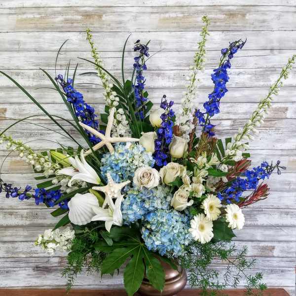 Blue and white floral arrangement in a bronze vase with starfish accents