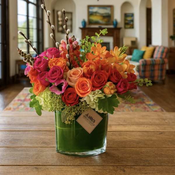 Bright mixed rose arrangement in a green glass vase