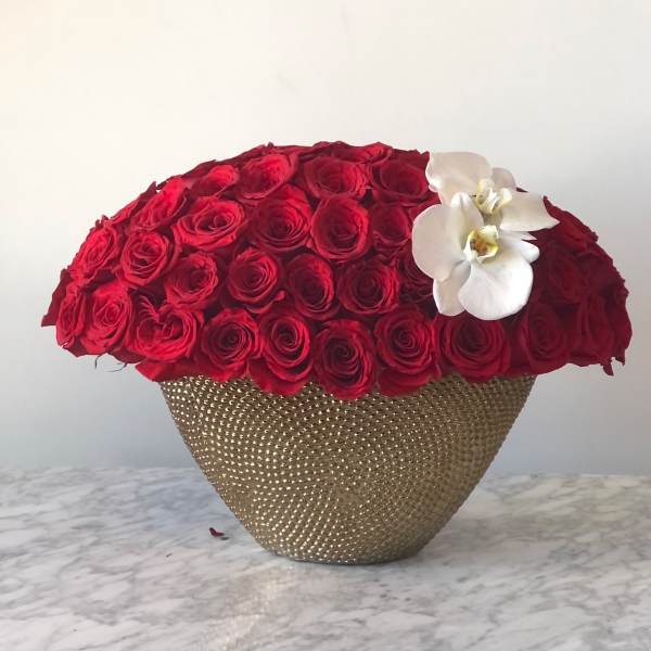 Red rose arrangement in a gold textured vase with white orchids