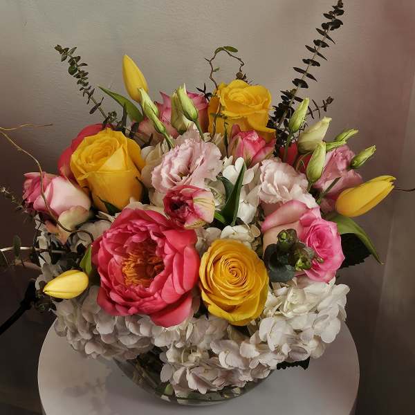 Bouquet of pink and yellow roses with white hydrangeas in a glass vase