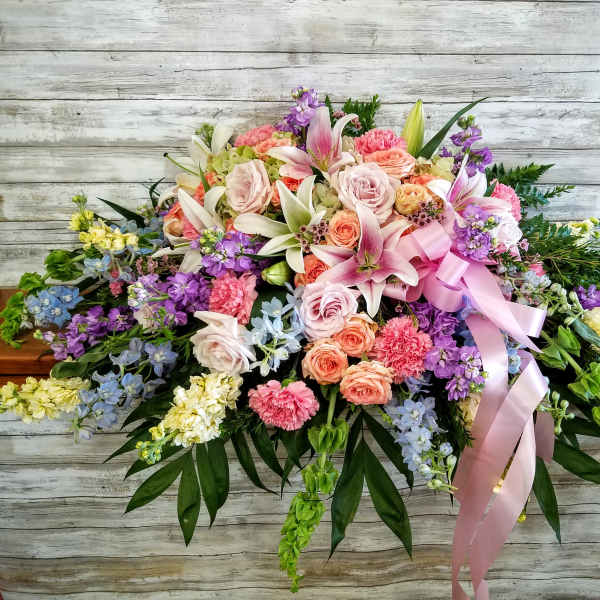 Large pastel floral spray with lilies, roses, and ribbon