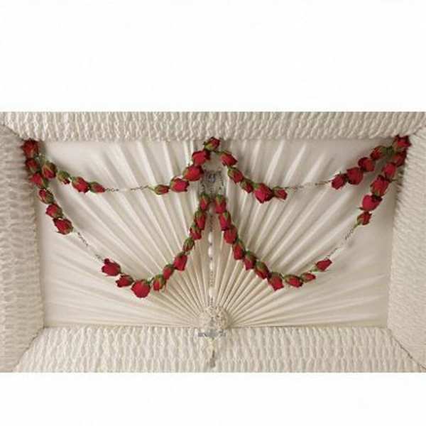 White coffin with red rose garlands arranged across the lid