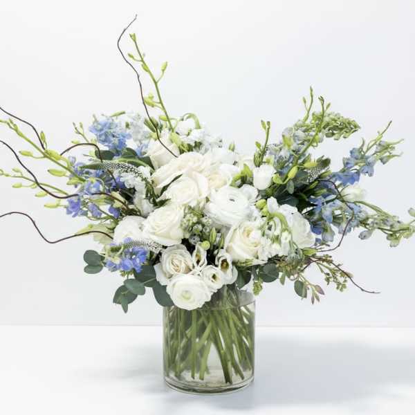 White and blue floral arrangement in a clear glass vase
