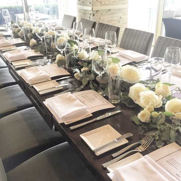 Long dining table set with white rose centerpieces and place settings