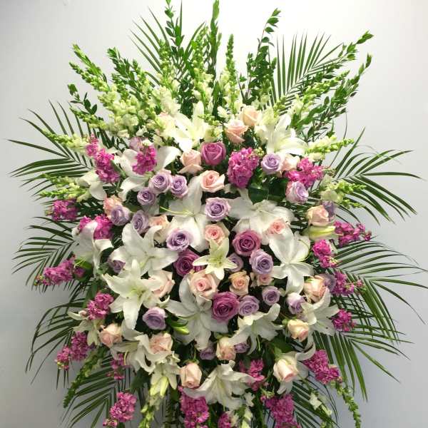 Standing floral spray with white lilies, pink and lavender roses, and magenta accents