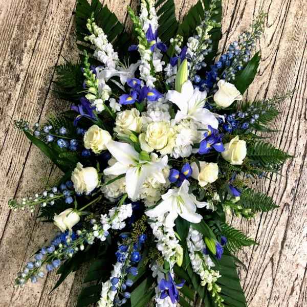 White lilies and blue flowers arranged in a cross shape