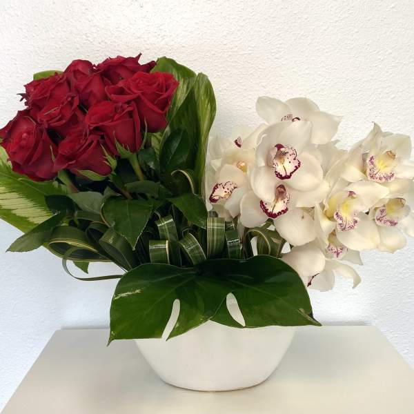 Red roses and white orchids in a white bowl vase