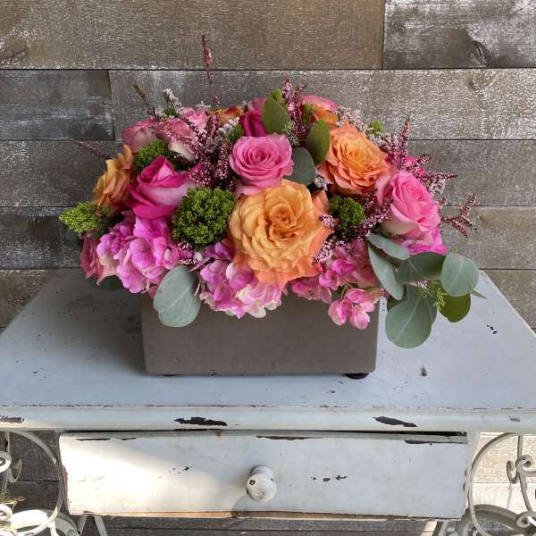 Pink and orange rose arrangement in a rectangular container