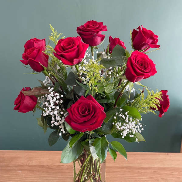Red roses arranged in a clear glass vase with baby's breath