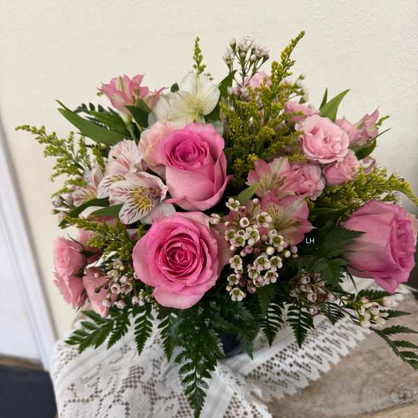 Pink roses and alstroemeria arranged in a vase with small white filler flowers