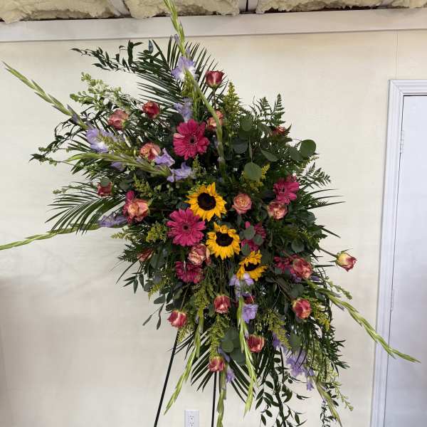 Large standing floral spray with sunflowers, pink gerberas, and roses
