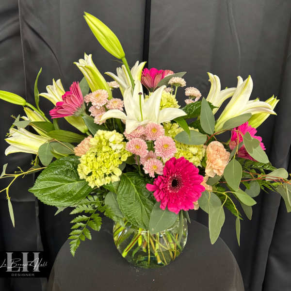 Mixed bouquet with white lilies, pink gerberas, and pale hydrangeas in a glass vase