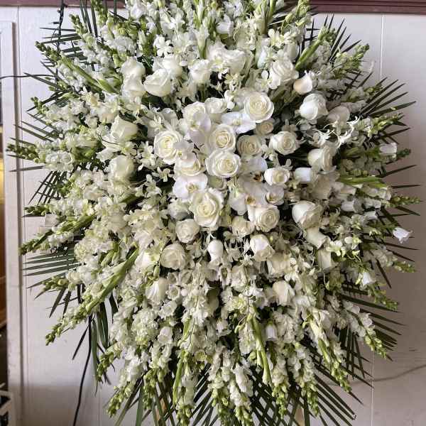 Large white funeral spray with roses and orchids on a standing easel
