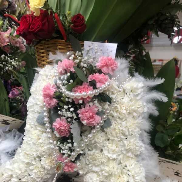 White floral funeral spray with pink carnations and pearl strands