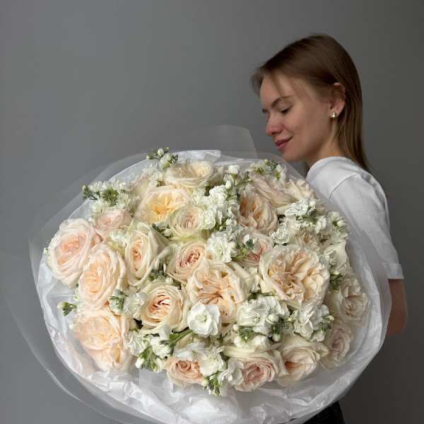 Large bouquet of pale peach and white roses wrapped in tissue paper