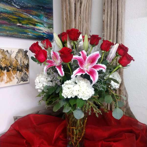Red roses and pink lilies arranged in a glass vase