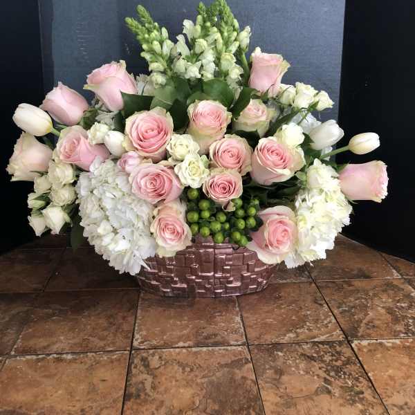 Pink roses and white flowers arranged in a woven basket