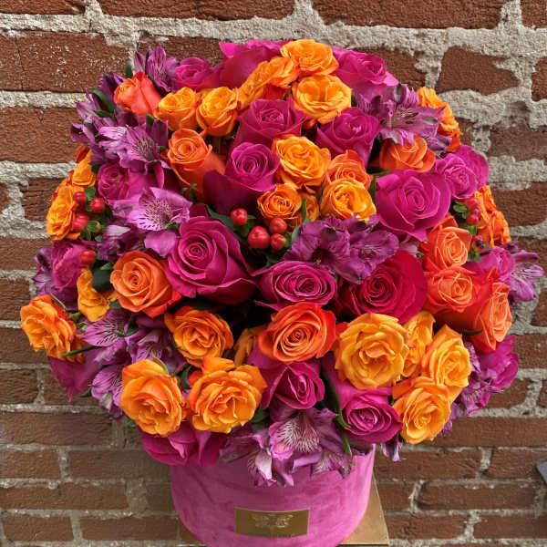 Round bouquet of pink and orange roses in a pink hat box