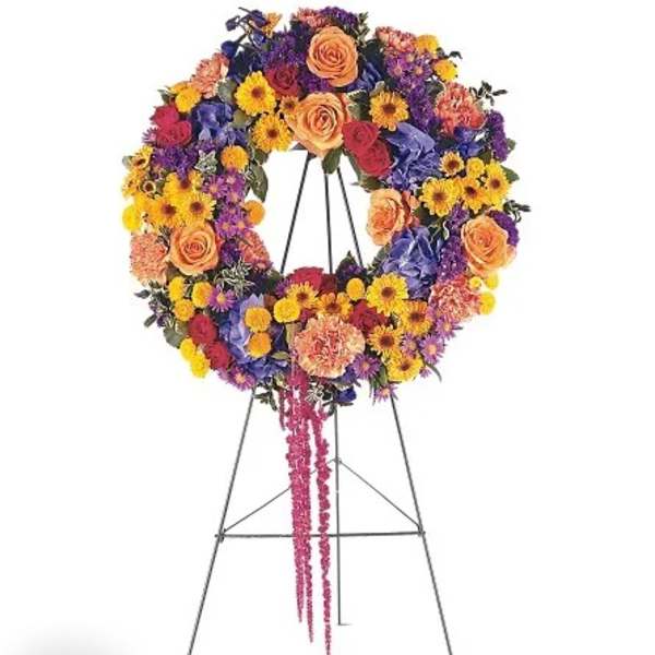 Colorful floral wreath on a standing easel with a pink ribbon tail