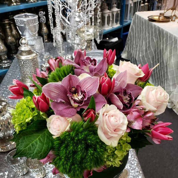 Pink orchids and roses arranged in a low vase with green accents