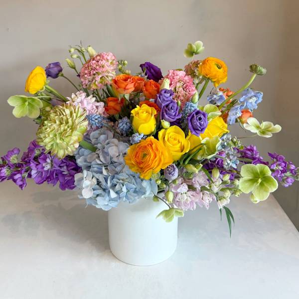 Colorful mixed bouquet in a white vase with roses and hydrangeas