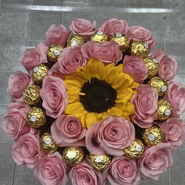 Pink roses and a sunflower arranged with gold-wrapped chocolates