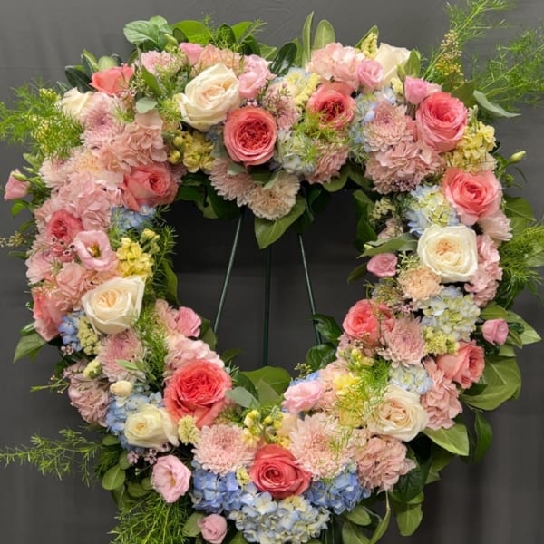 Heart-shaped floral wreath with pink and white roses and pastel blooms