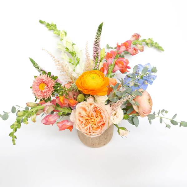 Colorful mixed flower arrangement in a small wooden container