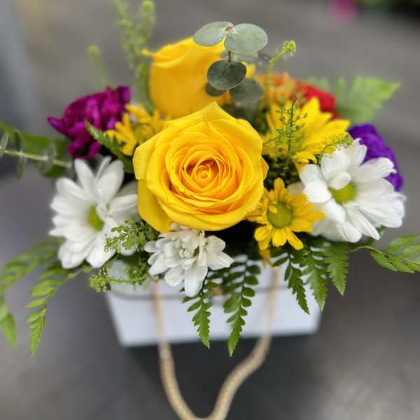 Yellow roses and white daisies in a white box with rope handles