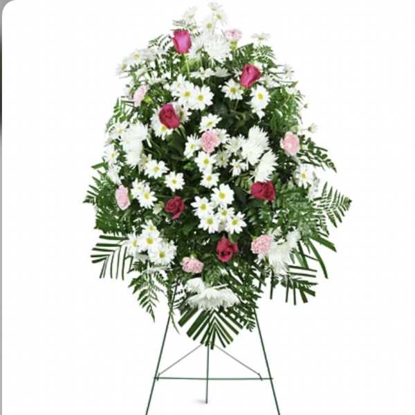 Standing floral spray with pink roses, white daisies, and greenery on an easel