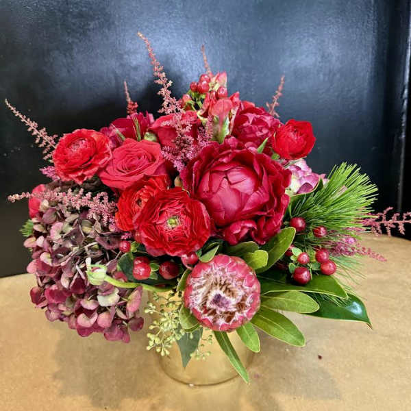 Red floral arrangement in a clear glass vase with pink accents