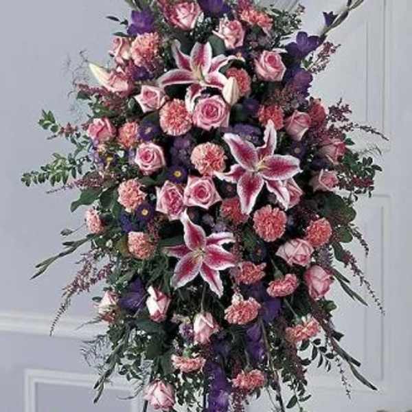Tall standing floral spray with pink roses and lilies in pink, purple, and white.
