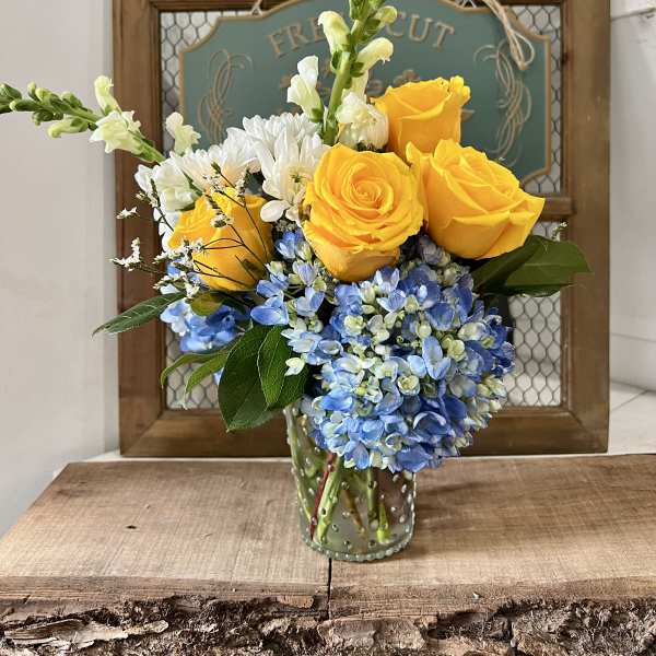 Yellow roses and blue hydrangeas in a glass vase