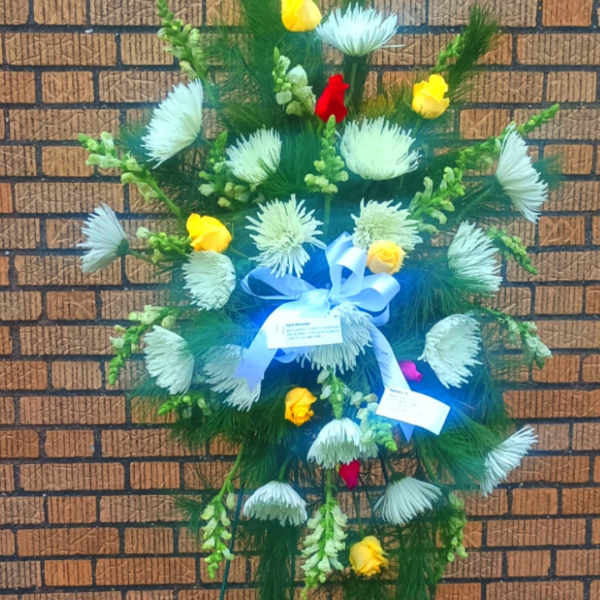 Standing floral spray with white blooms, yellow roses, and blue ribbon