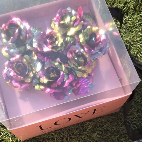 Pink gift box with iridescent artificial roses under a clear lid