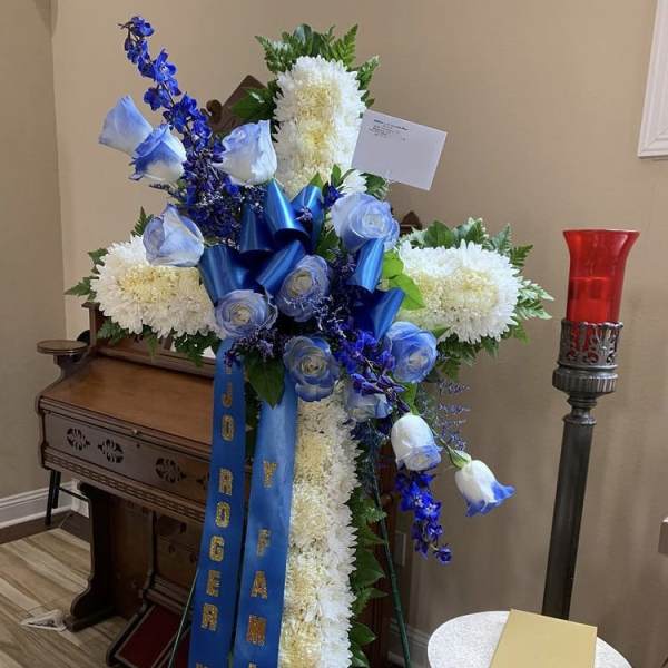 Standing funeral spray with white chrysanthemums, blue roses, and blue ribbons