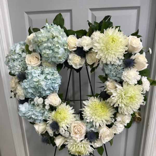 Heart-shaped floral wreath with blue hydrangeas, white roses, and pale chrysanthemums