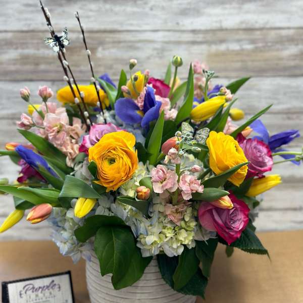 Colorful mixed bouquet in a white ribbed vase with tulips and roses
