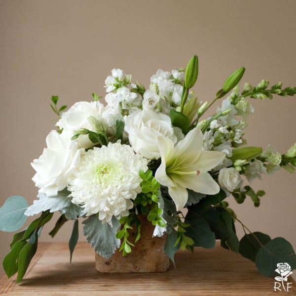 White roses and lilies arranged in a rustic vase