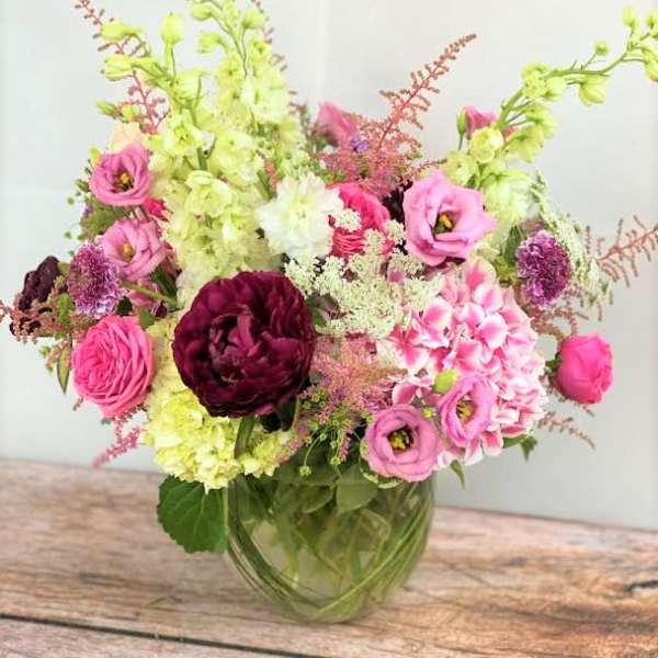 Pink and burgundy flowers arranged in a glass vase