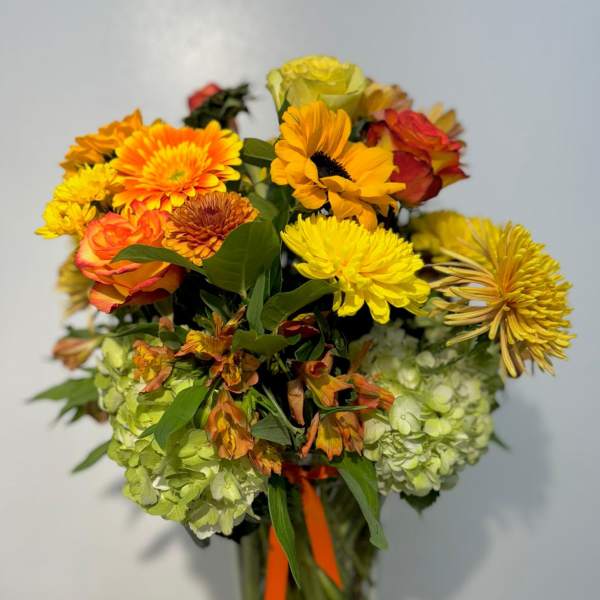 Mixed bouquet of yellow, orange, and red flowers in a glass vase