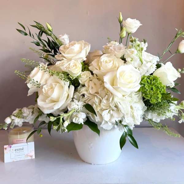 White roses and hydrangeas arranged in a white vase