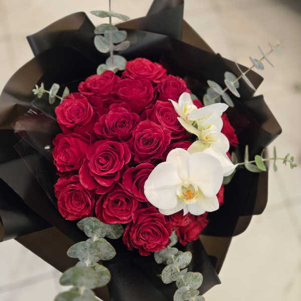 Bouquet of red roses with white orchids and dark wrapping