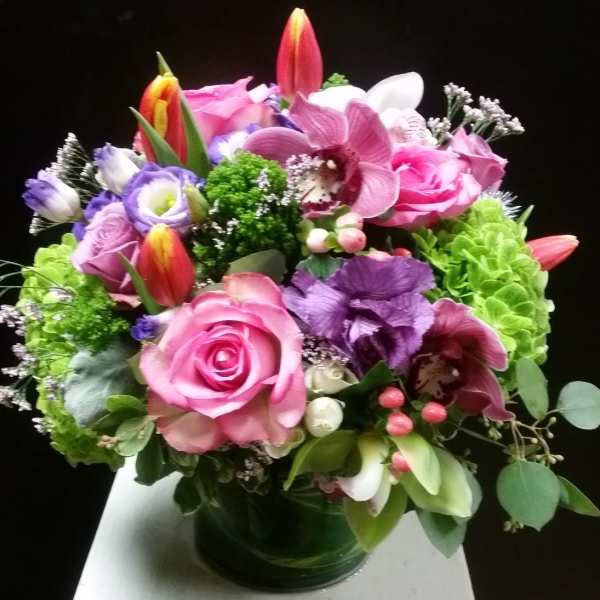 Mixed bouquet of pink, purple, and white flowers in a glass vase