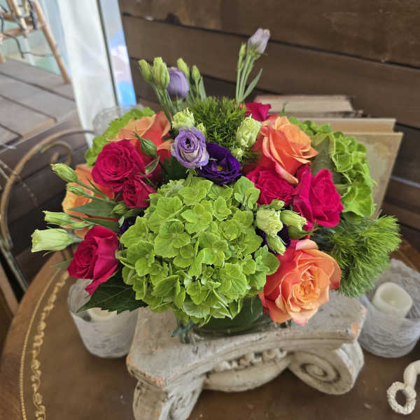 Bouquet of pink, orange, purple, and green flowers in a glass vase