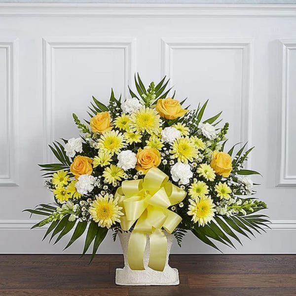 Yellow and white floral arrangement in a white vase with a yellow ribbon