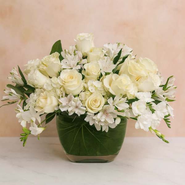 White roses and alstroemeria arranged in a green glass vase