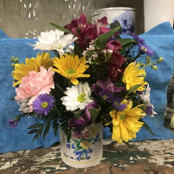 Mixed bouquet of daisies and alstroemeria in a decorated mug
