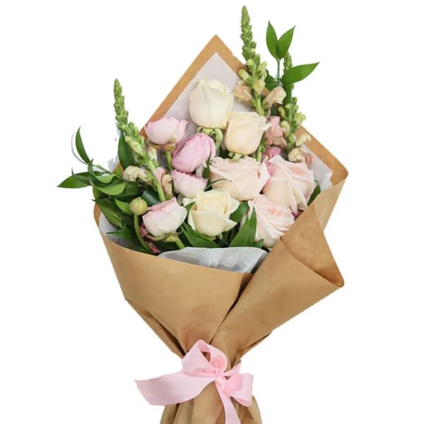 Bouquet of pale pink and white roses wrapped in brown paper with a pink ribbon
